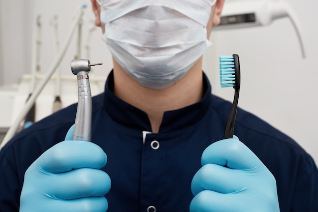 Young doctor holding dental tool and toothbrush