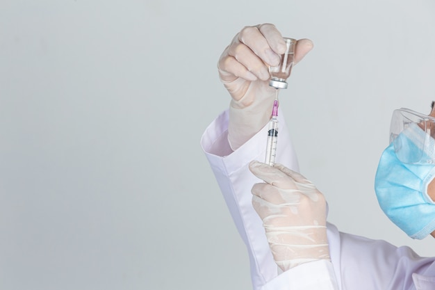 Free Photo young doctor is  holding  hypodermic syringe with  vaccine vial  rubber gloves on gray wall.