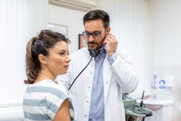 Young doctor is using a stethoscope listen to the heartbeat of the patient Shot of a male doctor giving a female patient a check up