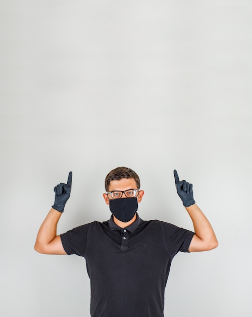 Free photo young doctor pointing fingers up in black polo shirt