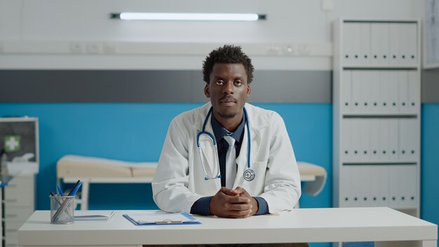 Young doctor talking on video call conference with patient for remote online consultation while sitting at desk in cabinet. Medic using internet communication for telemedicine treatment