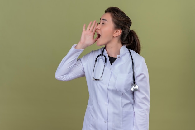 young doctor wearing medical gown wearing stethoscope - on green wall