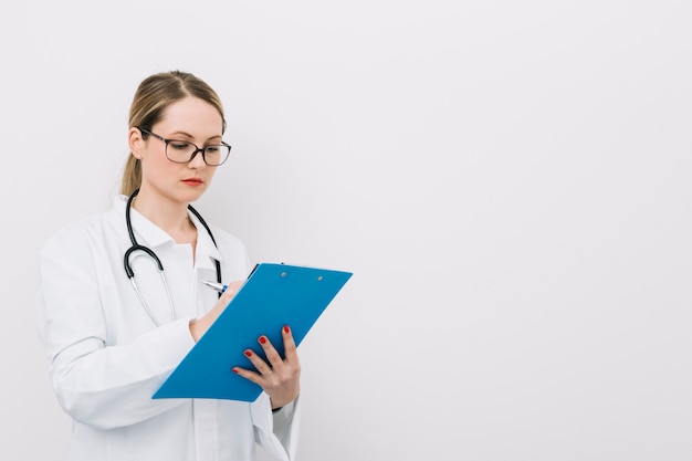 Young doctor writing on clipboard