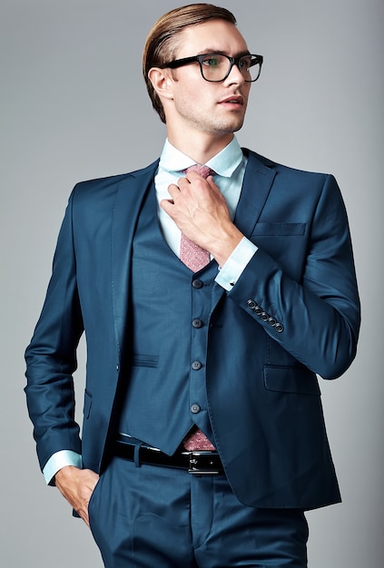 Young elegant handsome businessman male model in blue suit and fashionable glasses, posing in studio