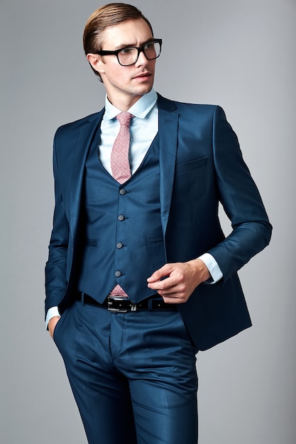 Free photo young elegant handsome businessman male model in blue suit and fashionable glasses, posing in studio