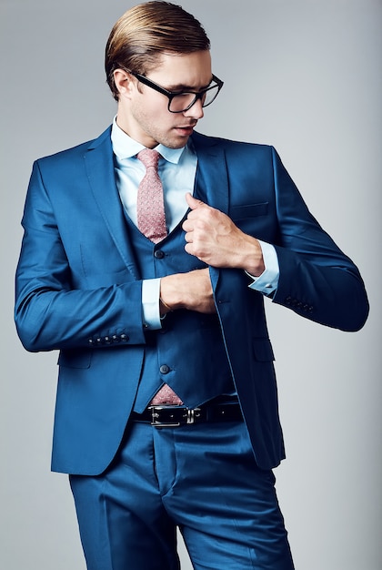 Free photo young elegant handsome businessman male model in blue suit and fashionable glasses, posing in studio