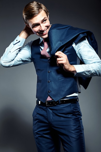 Young elegant handsome businessman male model in blue suit posing in studio