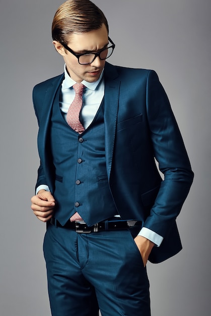 Young  elegant handsome  businessman male model in a suit and fashionable glasses, posing in studio