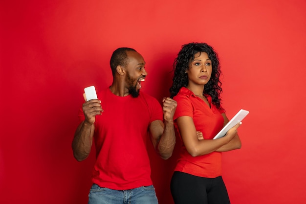 Young emotional african-american man and woman on red