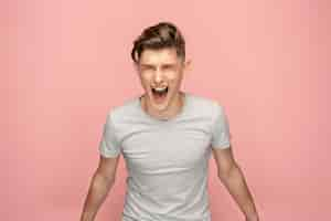 Free photo the young emotional angry man screaming on pink studio space