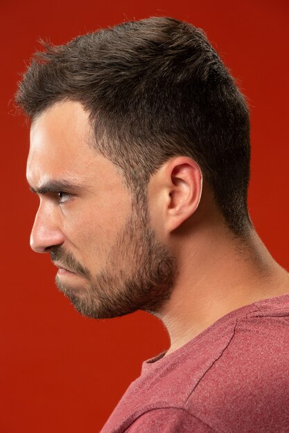 The young emotional angry man screaming on red studio wall