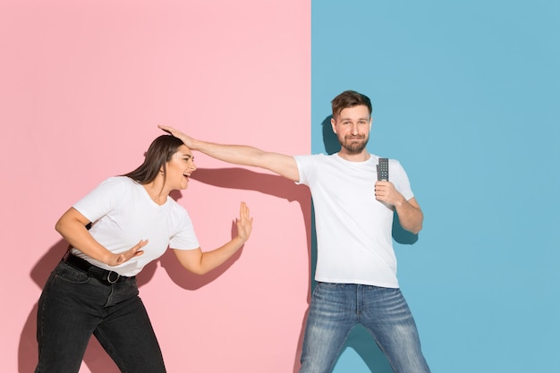 Free photo young emotional man and woman on pink and blue wall