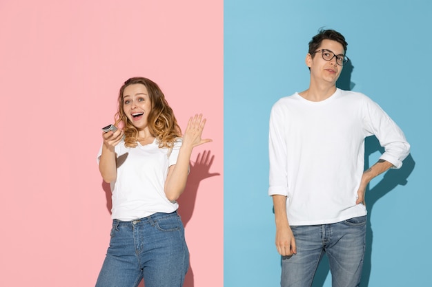 Young emotional man and woman on pink and blue