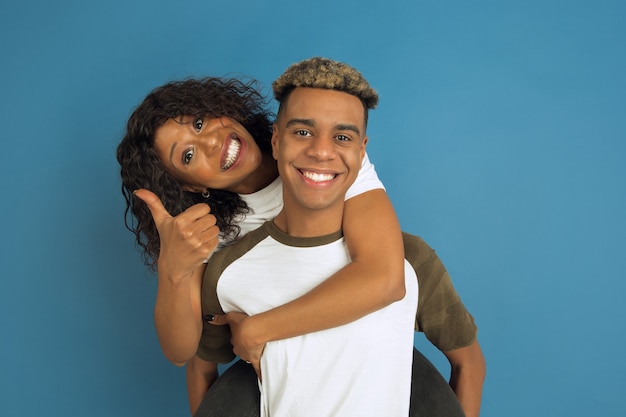 Young emotional man and woman in white casual clothes posing on blue.