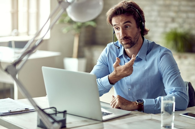 Young entrepreneur communicating with someone while having video conference in the office