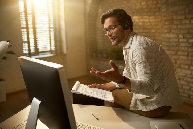 Free photo young entrepreneur talking about business reports while having video conference over desktop pc at the office