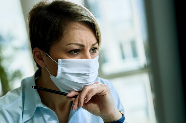 Young entrepreneur wearing face mask while working in her office