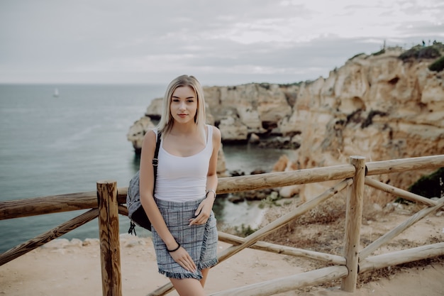 Young european female tourist with a backpack looking at the sea