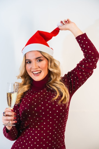 Free photo young fair-haired lady in a santa hat making a festive toast