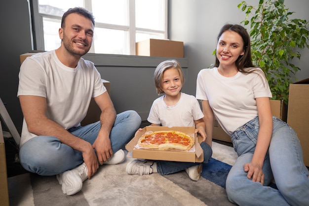 Free photo young family moving into a new home and eating pizza