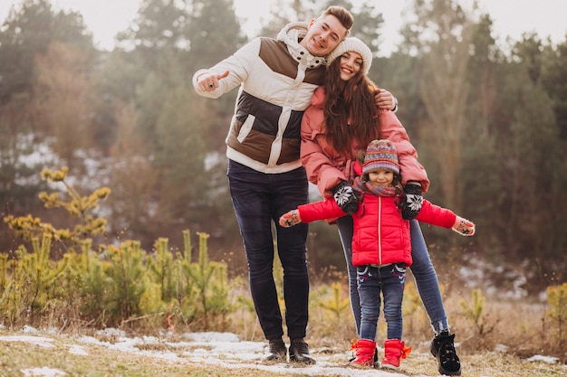 Young family together walking in forest at winter time