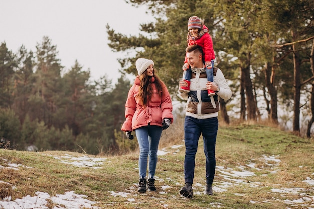 Young family together walking in forest at winter time