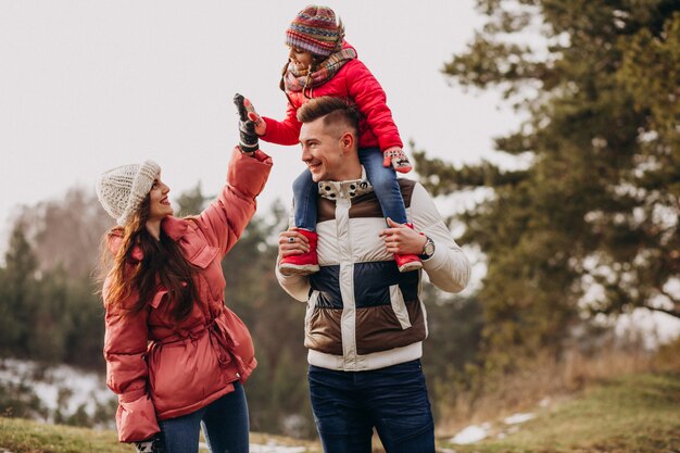 Young family together walking in forest at winter time