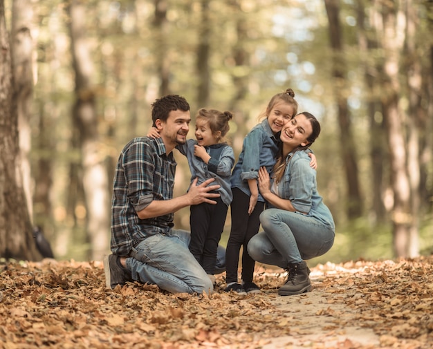 A young family walks in the autumn forest with children.