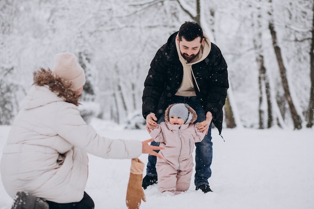 Young family with little daughter in a winter forest full of snow