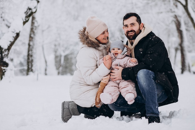 Young family with little daughter in a winter forest full of snow