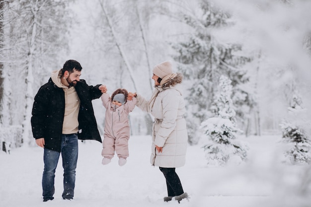 Young family with little daughter in a winter forest full of snow