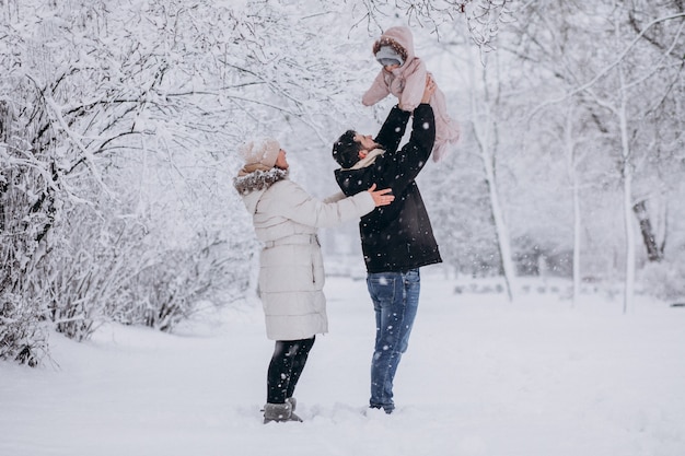 Young family with little daughter in a winter forest full of snow