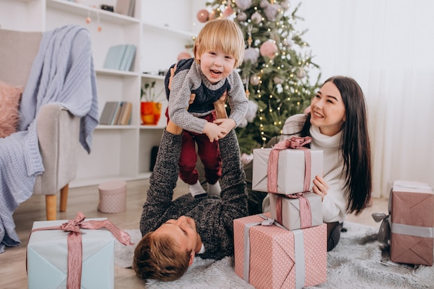 Young family with little son by Christmas tree