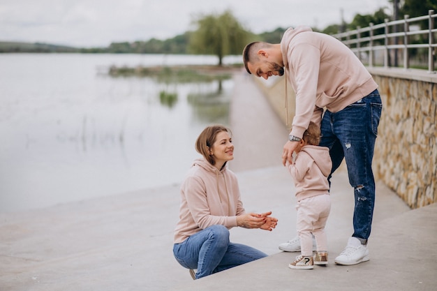 Young family with their little baby child in park by the lake