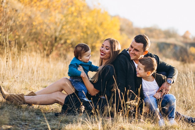 Free photo young family with two sons together sitting in park