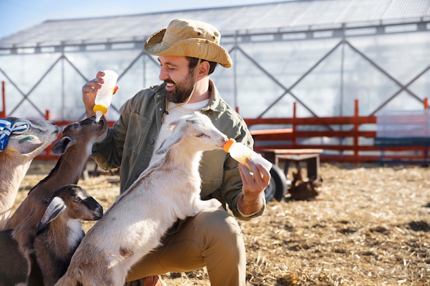 Free Photo young farmer feeding his goats milk from a bottle at the farm