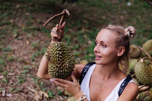 Young fashion woman on a tropical field with durian fruits