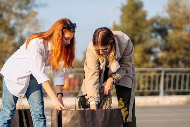 Young fashion women with shopping bags on parking