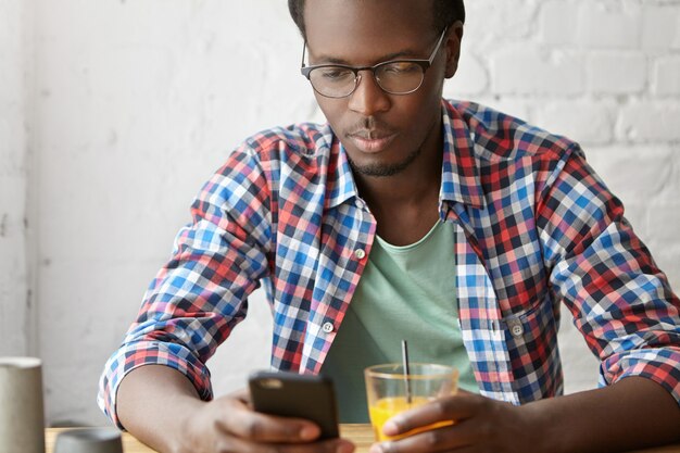 young fashionable guy sitting at a cafe with phone