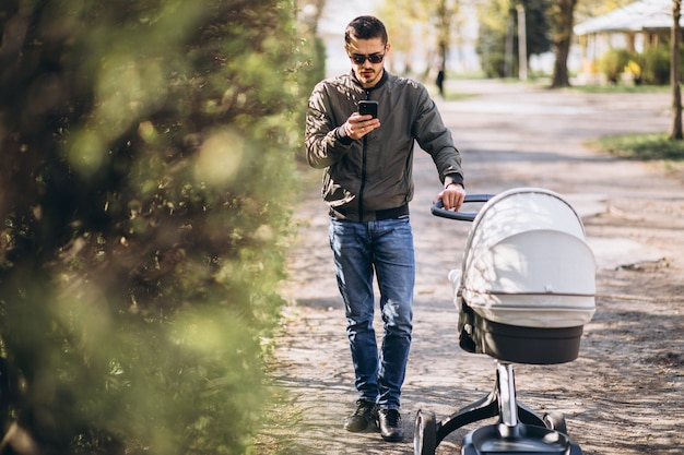 Young father walking with baby carriage in the park