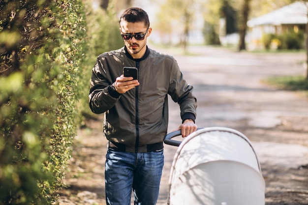 Young father walking with baby carriage in the park