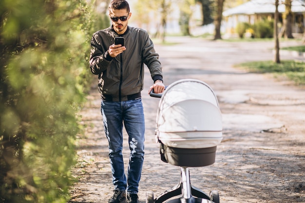 Young father walking with baby carriage in the park