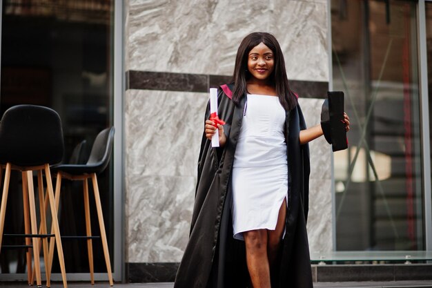 Young female african american student with diploma poses outdoorsxA