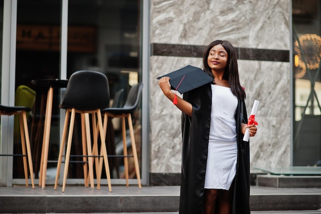 Young female african american student with diploma poses outdoorsxA