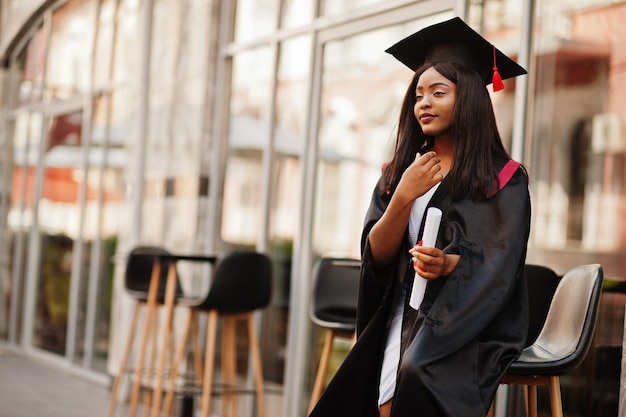 Young female african american student with diploma poses outdoorsxA