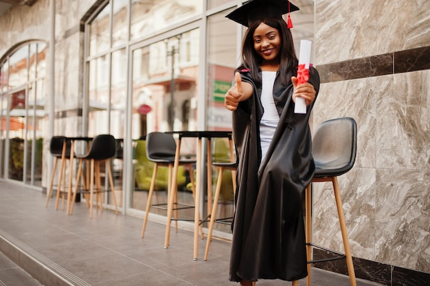 Young female african american student with diploma poses outdoorsxA