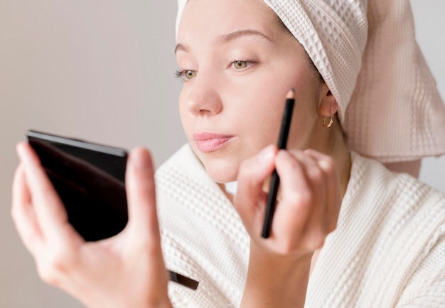 Young female applying eyeliner