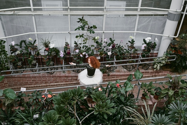 Free Photo young female ballerina dancing in an indoors botanical garden