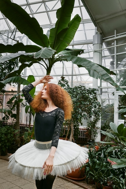 Free photo young female ballerina dancing in an indoors botanical garden