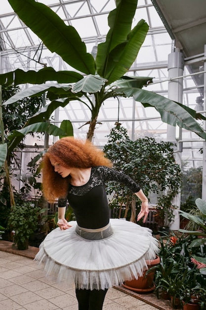 Free photo young female ballerina dancing in an indoors botanical garden